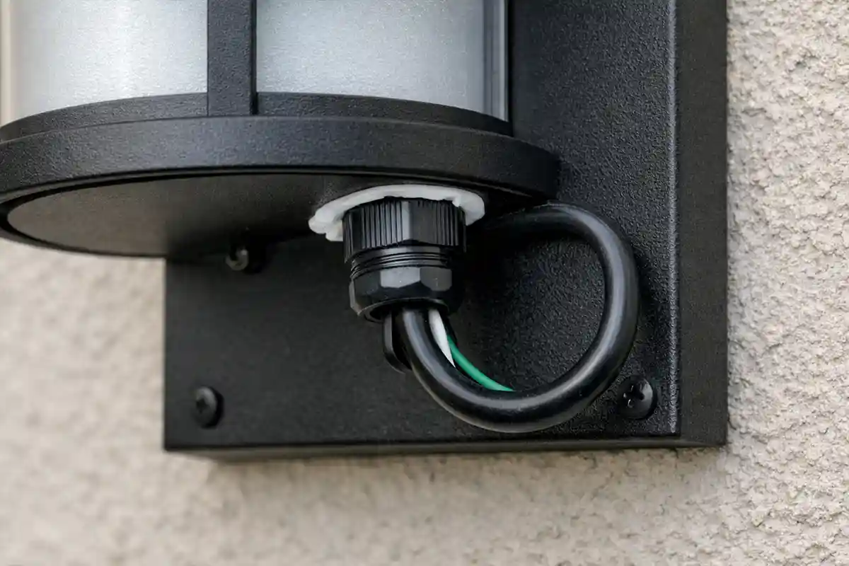 Outdoor light fixture with properly sealed cable entry point and visible drip loop preventing water intrusion.